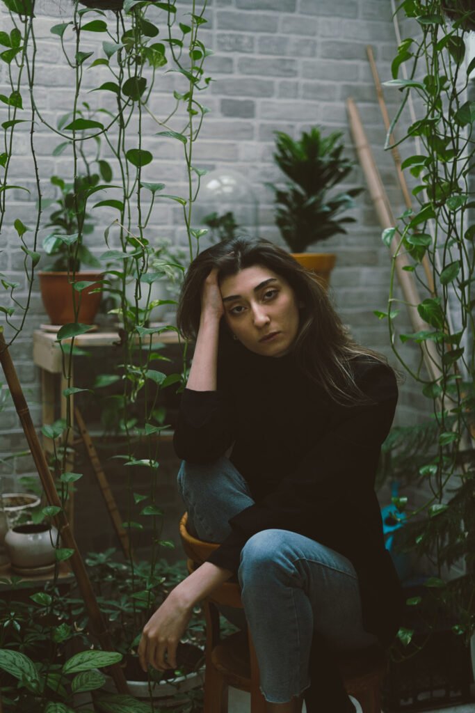 Mubie resting her head on her hand in a plant-filled room