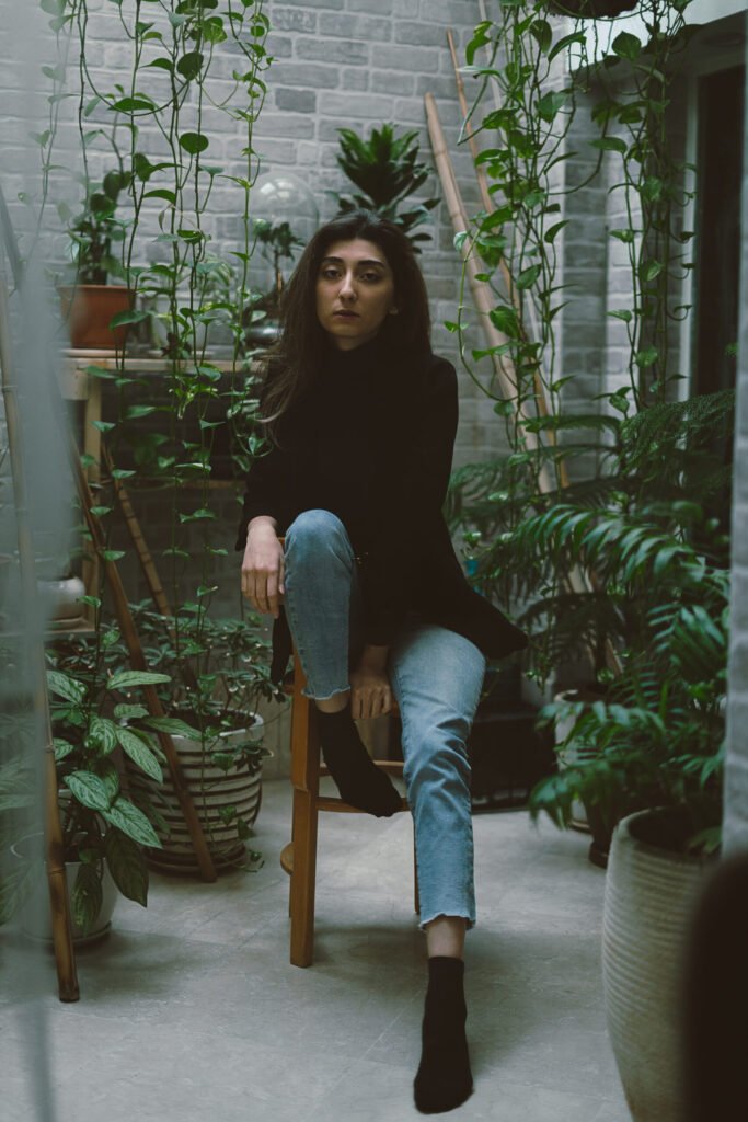 Full-length portrait of Mubie seated among indoor plants