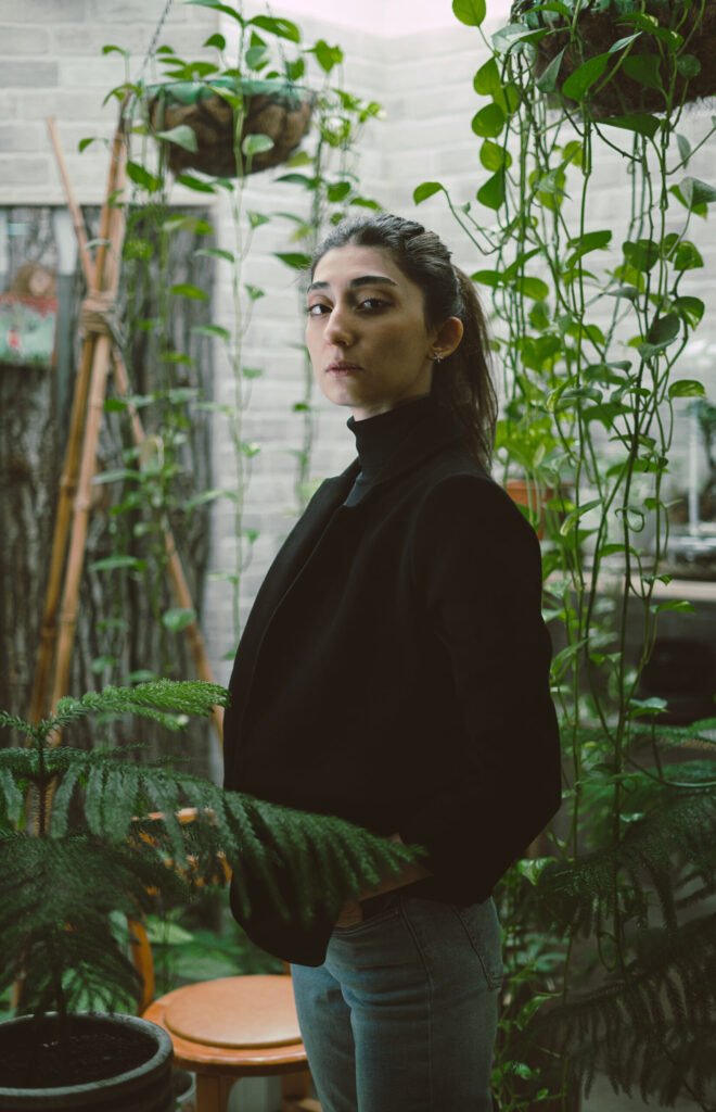 Portrait of Mubie standing in a garden room with green plants