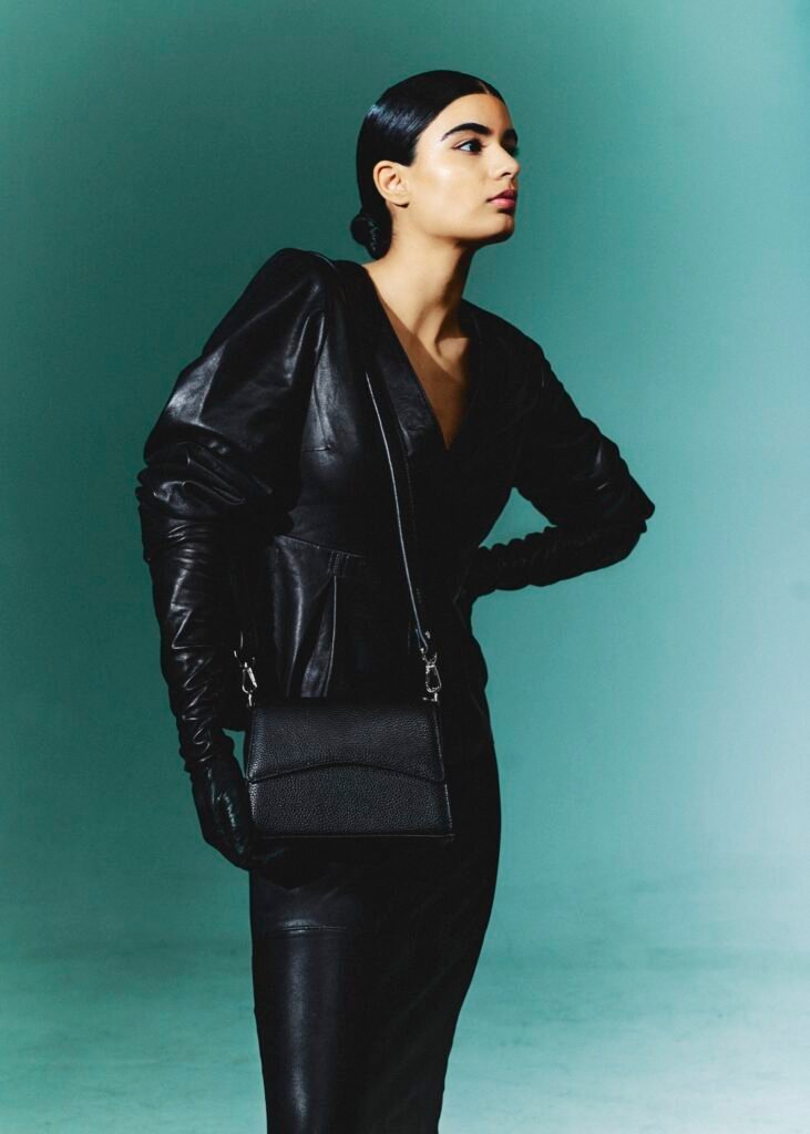 Model carrying a small black leather shoulder bag