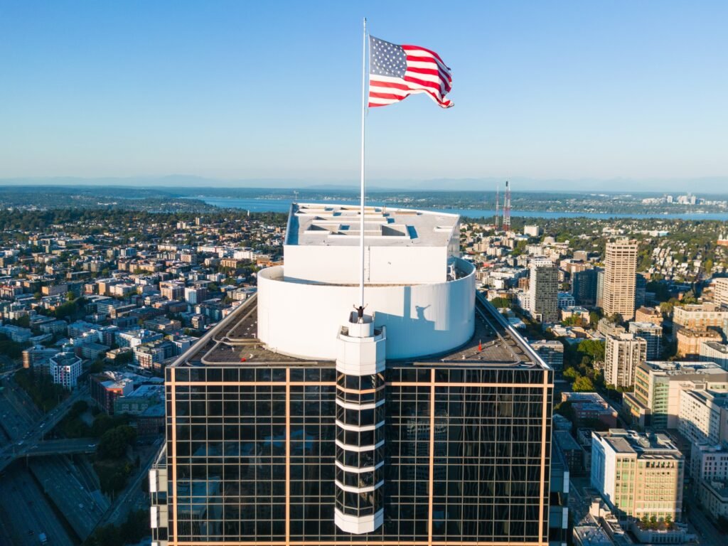 Urban explorer beside a large American flag on a high-rise rooftop
