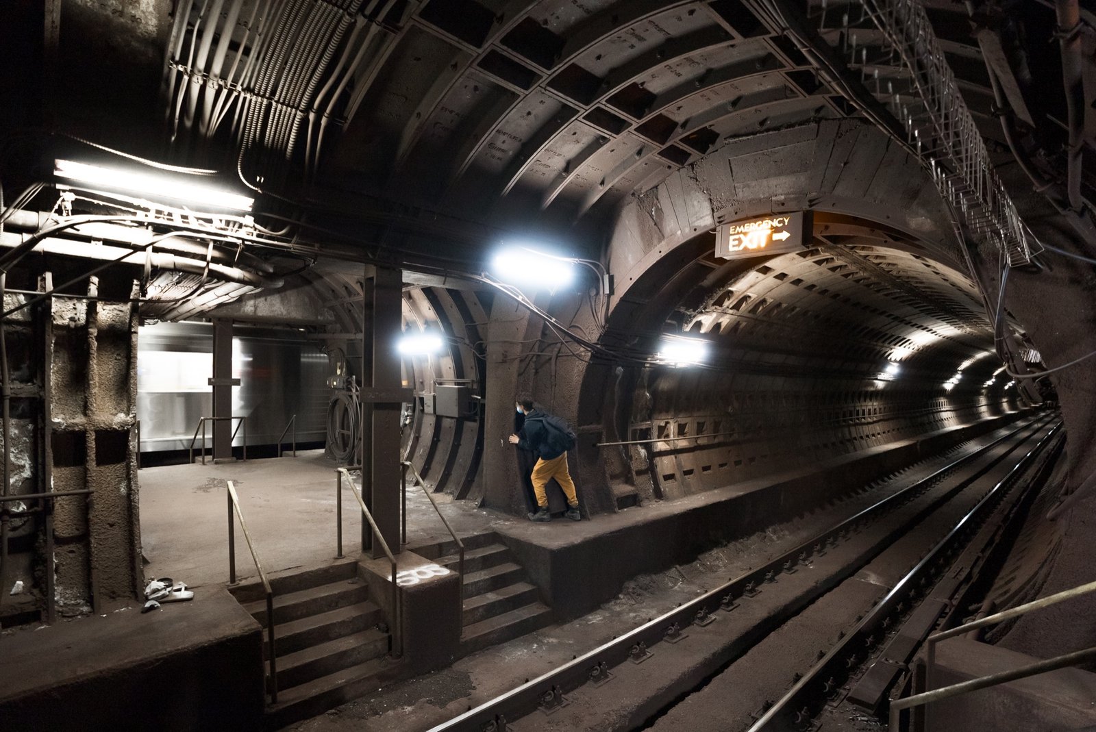 Urban explorer standing beside a moving subway train inside a dark tunnel