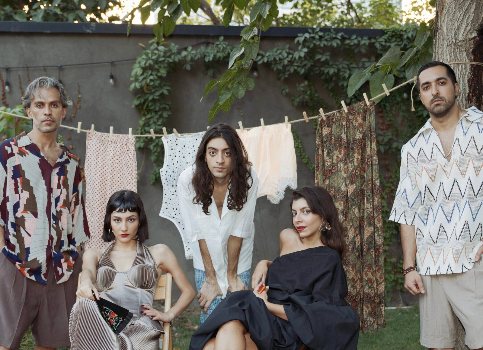 the band sitting in a garden posing for the camera